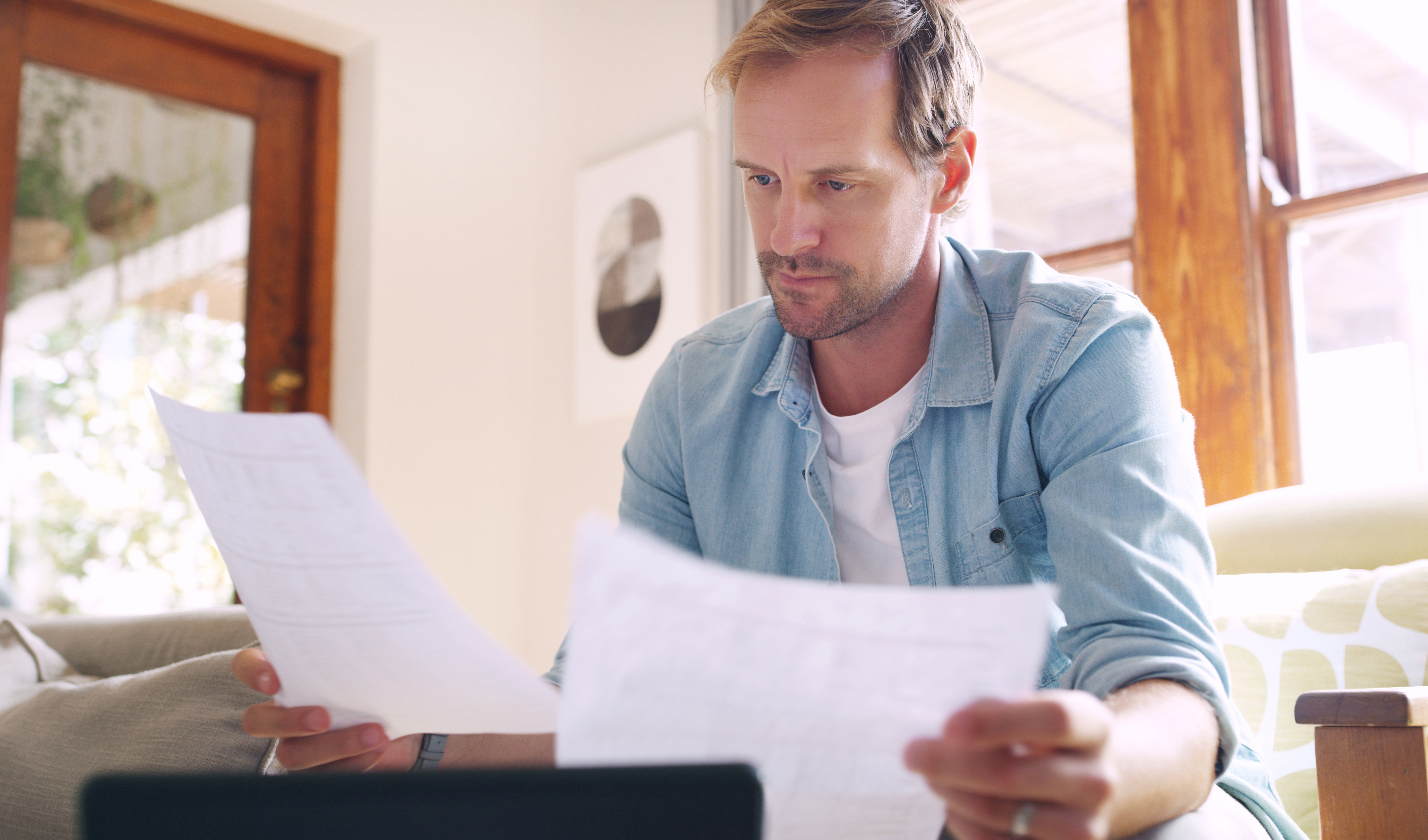 Man reviewing parking charge paperwork at home with laptop